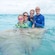 A family posing in the water with a stingray at Safehaven Marine in Grand Cayman